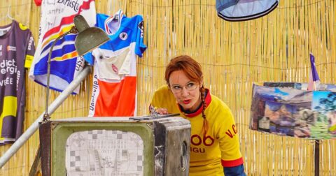 une comédienne est positionnées derrière une vielle télévision