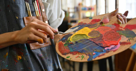 une dame tient une palette de peinture et un pinceau