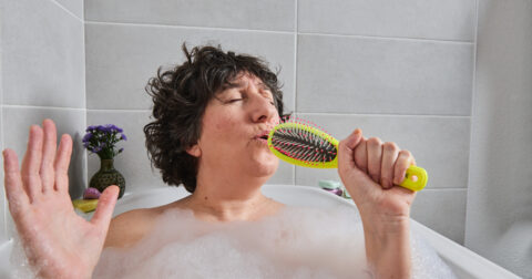 Une comédienne chante avec une brosse à cheveux dans son bain
